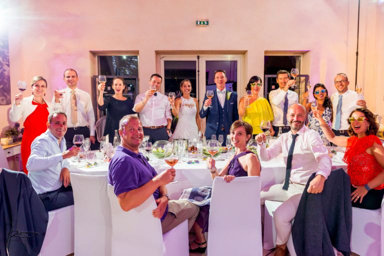 Photographe mariage Var. photographe mariage Hyères. Les invités portent un toast aux mariés à la table d'honneur.