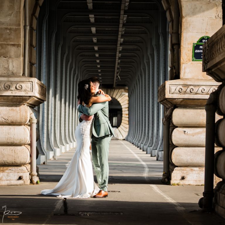 Couple de mariés marocains s’enlaçant sous les arcades du pont Bir-Hakeim à Paris, photographiés en plan serré à 200mm.