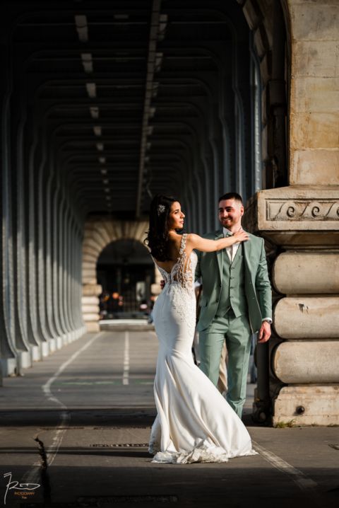 Mariée marocaine en robe blanche posant avec grâce pendant que son mari rit avec tendresse, scène capturée à Paris.