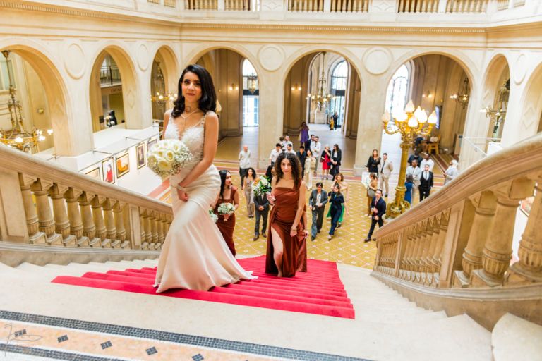 Mariée marocaine souriante montant l'escalier de la mairie du 10e Paris